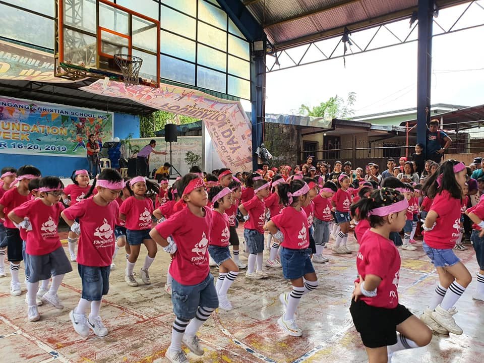 Pupils in red performing a dance number on stage